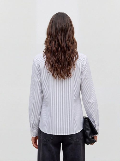Camisa branca às riscas finas pretas na modelo, vista de trás