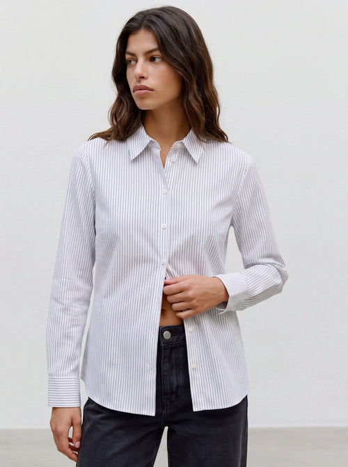 Modelo com camisa branca às riscas finas pretas e calças escuras