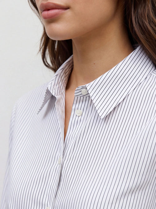 Detalhe da gola e dos botões da camisa branca às riscas finas pretas