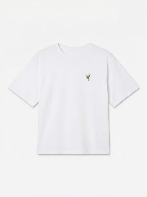 T-shirt branca de manga curta com pequeno motivo vegetal no peito, vista de frente